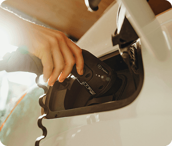 Mano che collega il cavo di ricarica a un’auto elettrica