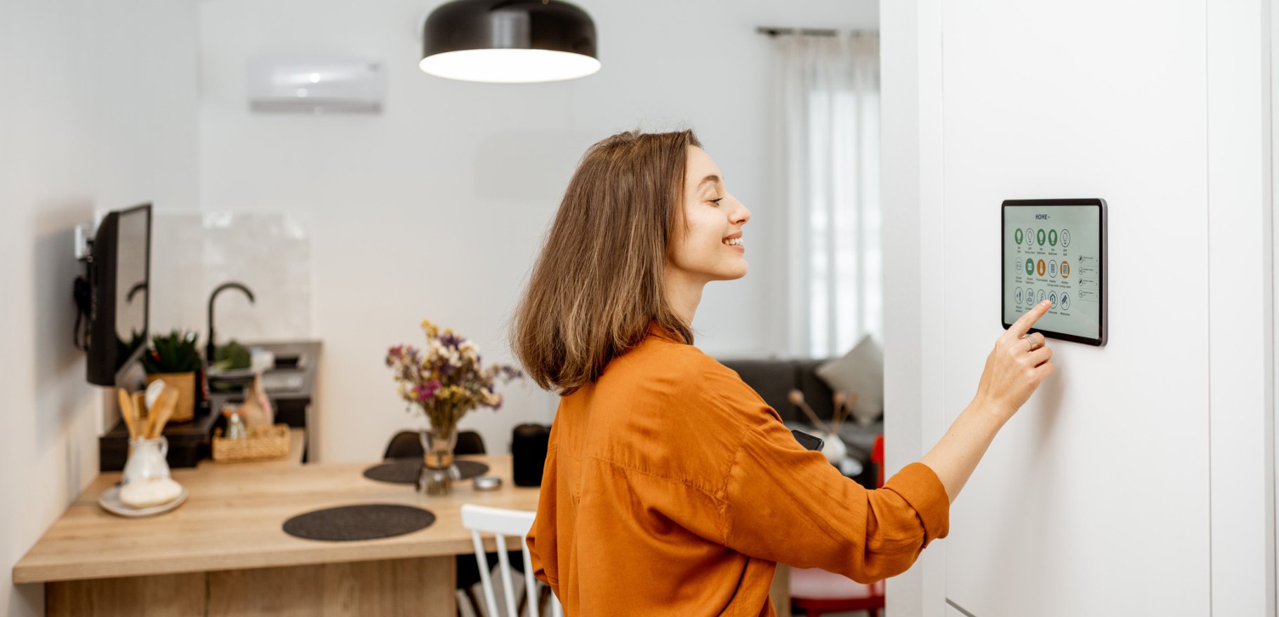 Donna che regola un termostato smart a parete in cucina
