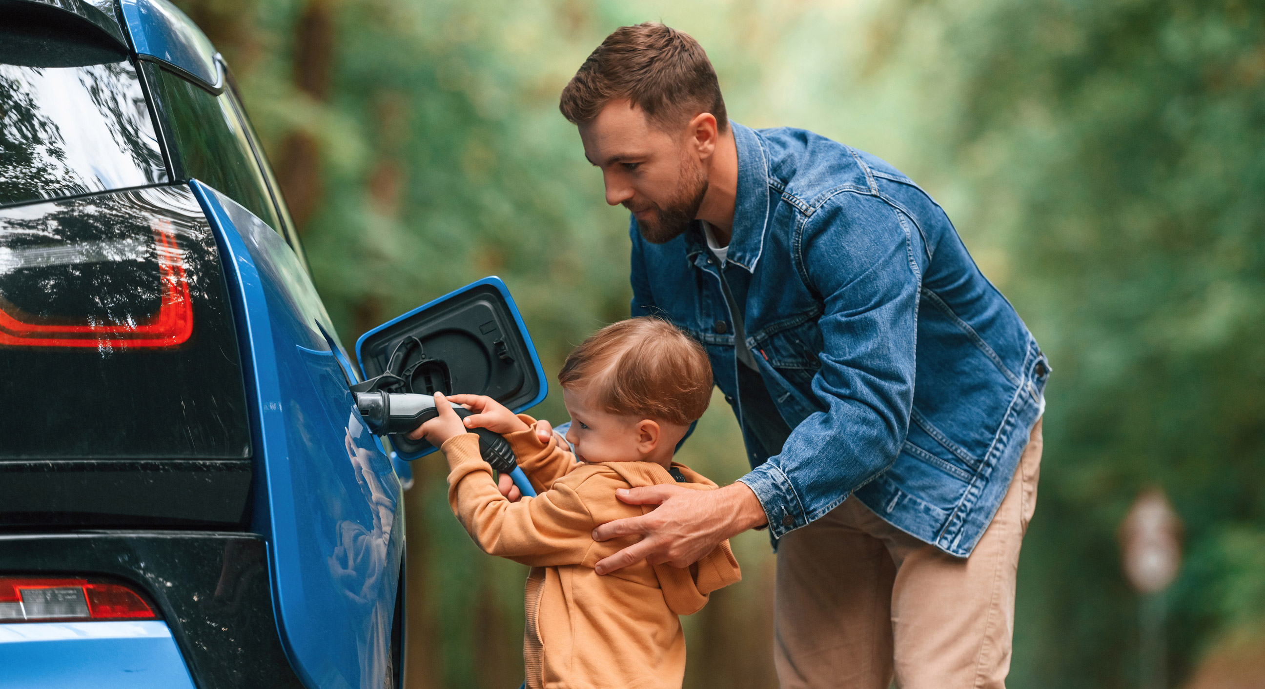 Padre e bambino mettono in carica l’auto elettrica di famiglia